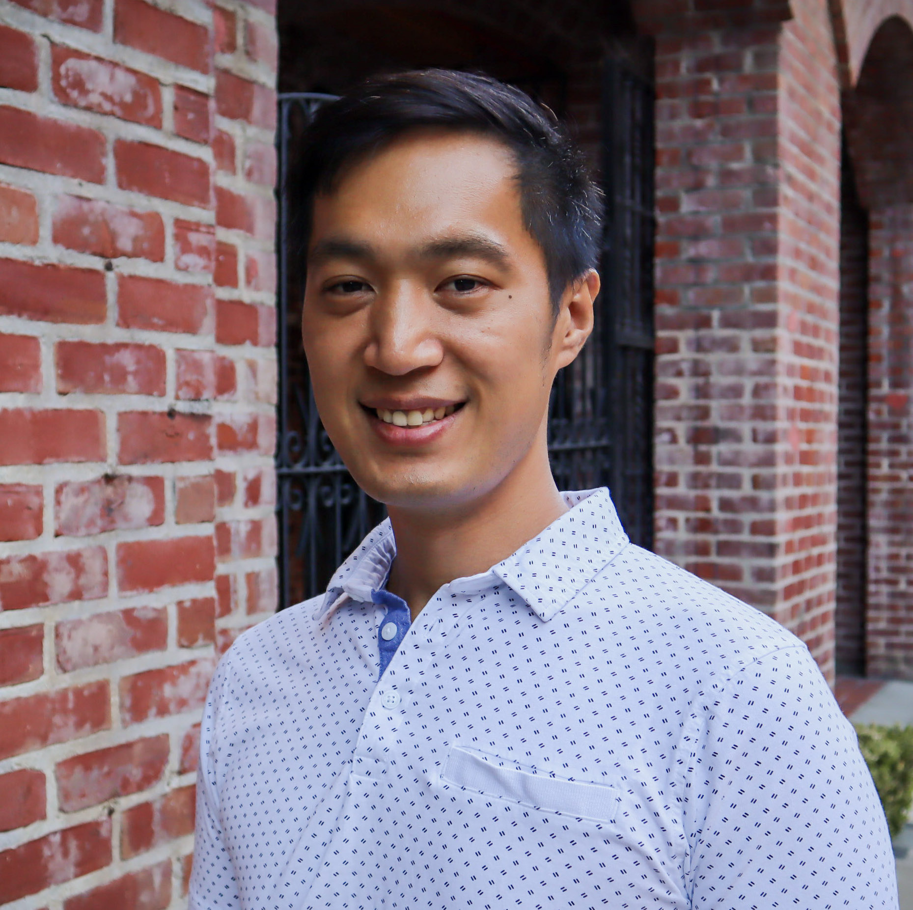 Michael Lin smiling, wearing jacket and blue lake in background.