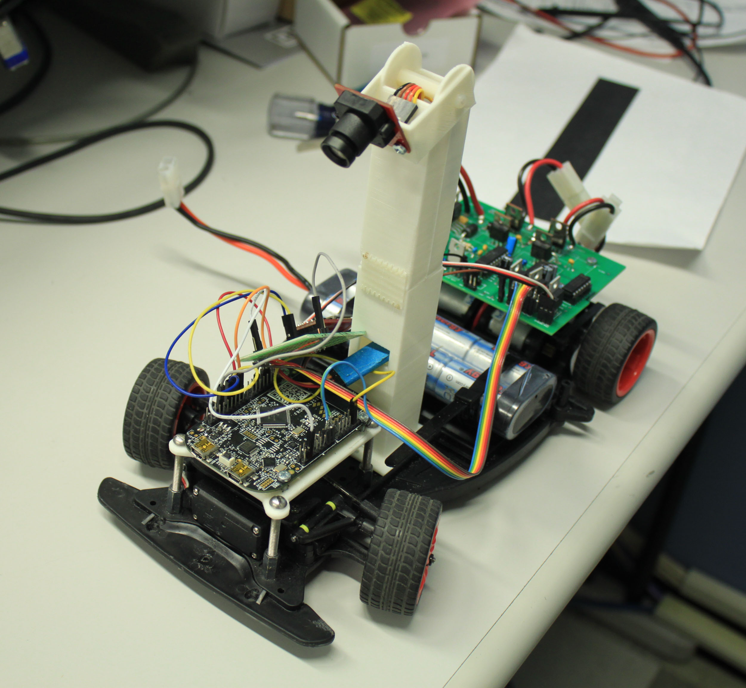 An RC car with custom electronics and a camera mounted on a mast.