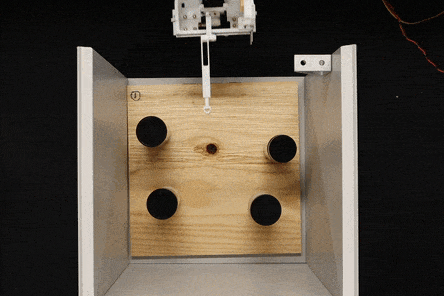 A GIF image showing a robot gripper moving inside a cabinet and making contact with four spice jars quickly, and then grasping one of the spice jars.